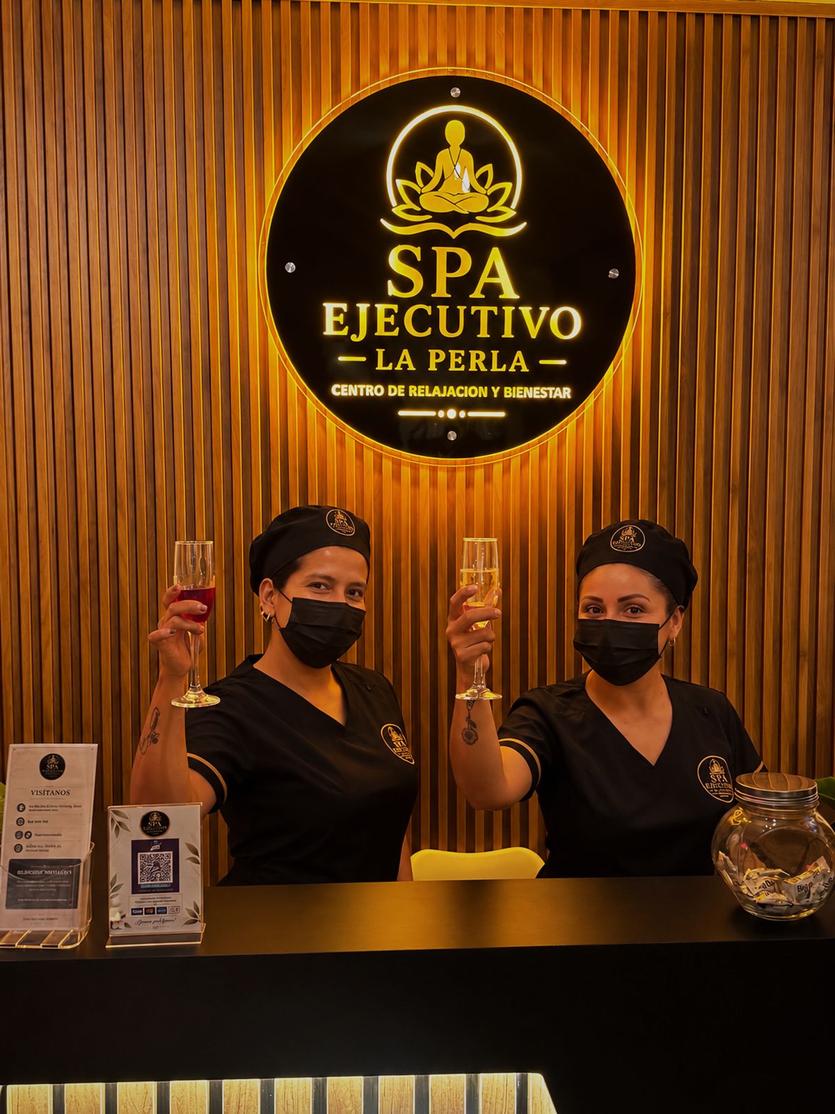 Dos integrantes del equipo brindan en la recepción, bajo el logo iluminado